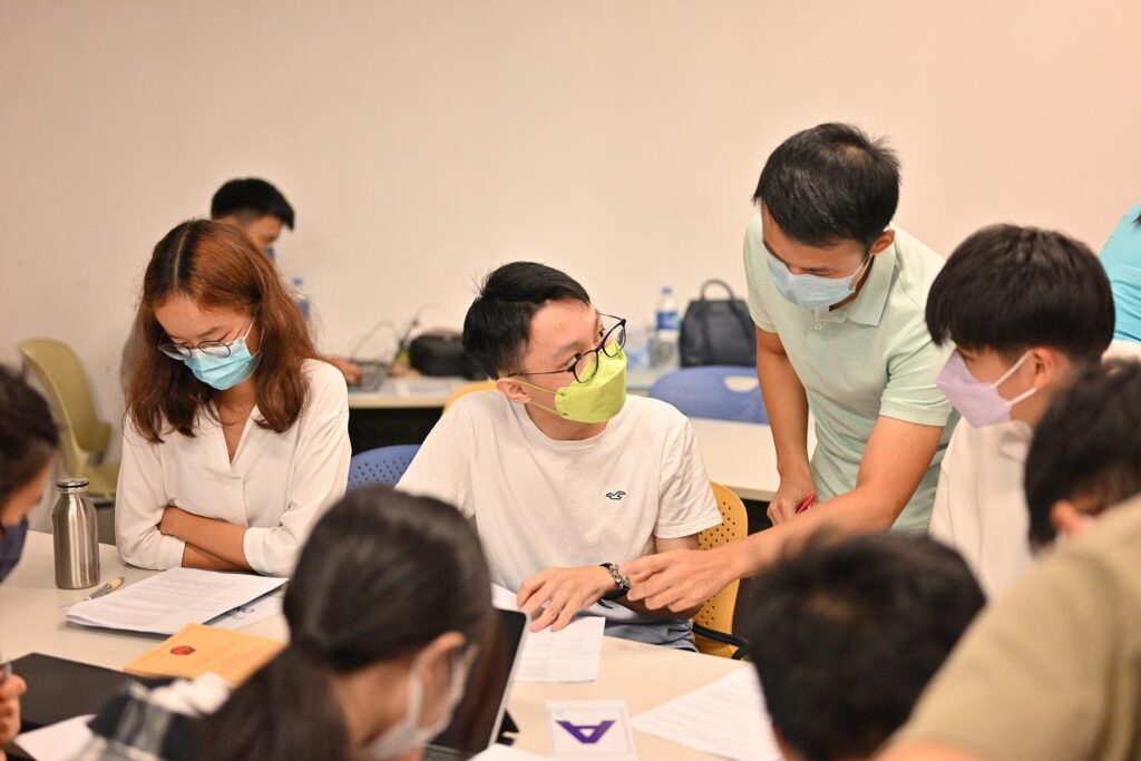 Group of students with masks discussing over papers in an accessible legal education classroom setting.