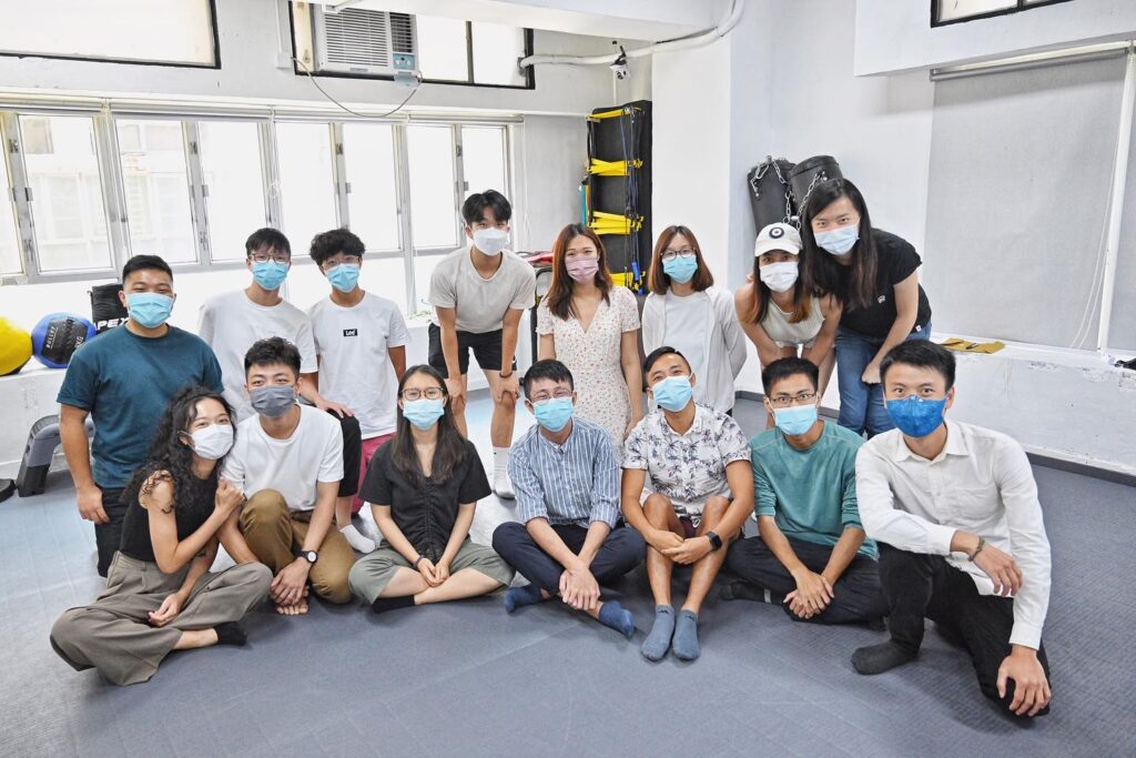 Group of fifteen people wearing face masks posing for a photo in a law classroom setting.